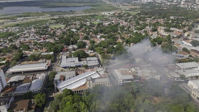 Drone approaches smoke coming from neighborhood near Central Station Railway Museum in Asuncion, Paraguay
