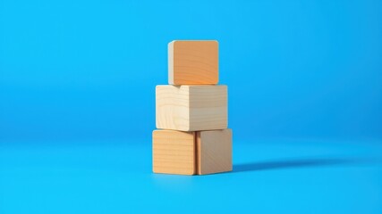 Obraz premium A stack of three wooden blocks on a blue background, representing simplicity, stability, and potential.