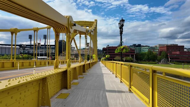Immerse yourself in the vibrant ambiance of a summer day in Pittsburgh with this POV Steadicam footage. This clip takes you on a walk across a yellow steel bridge, capturing the bustling traffic. 