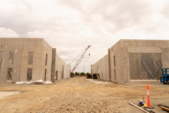 Tilt-up warehouse being constructed of prefabricated concrete panels with walls temporarily supported by stays and props.