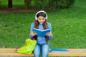 School amazed girl read book and listen audiobook outdoor. Back to school. Education and knowledge. Girl listen audiobook and read book. Audiobook vs book. Student girl. School education