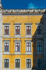 Sunlight is illuminating the yellow facade of mafra national palace in portugal, creating a captivating play of light and shadow on the windows and architectural details