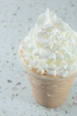 A view of a frozen cappuccino drink, topped with whipped cream.