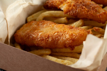 A closeup view of a box container of fish and chips.