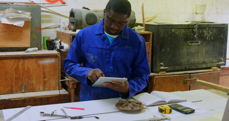 Male worker using digital tablet in foundry workshop