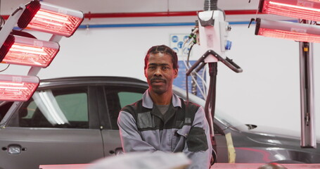 Portrait of an African American male car mechanic working in a township workshop, crossing his arms