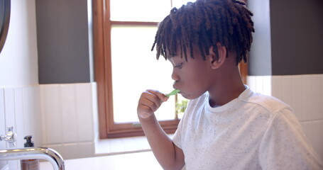 African american boy brushing teeth in bathroom at home, slow motion
