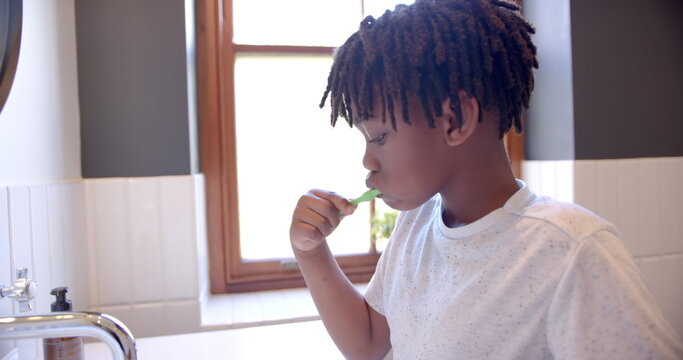 African american boy brushing teeth in bathroom at home, slow motion