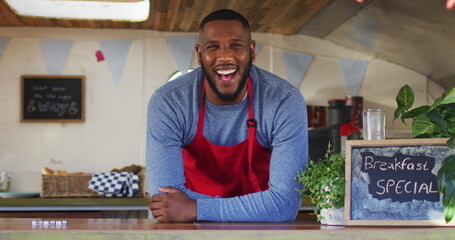 Portrait of african american man wearing apron smiling while standing in the food truck