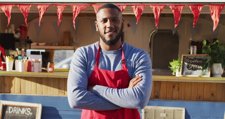 Portrait of african american man with arms crossed smiling while standing near the food truck