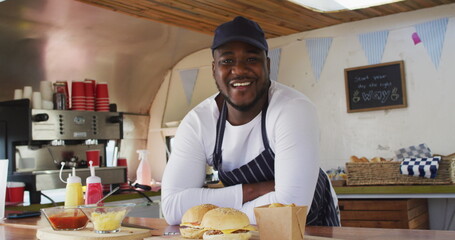 Portrait of african american man wearing apron smiling while standing in the food truck