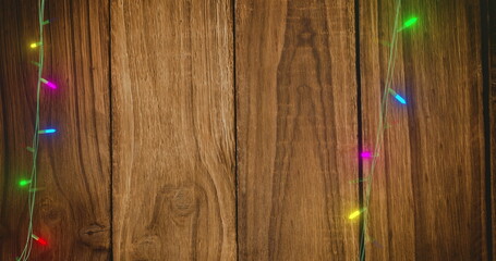 Image of flickering fairy lights with copy space on wooden background