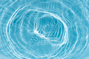 Blue water with ripples on the surface. Defocus blurred transparent blue colored clear calm water surface texture with splashes and bubbles. Water waves with shining pattern texture background.