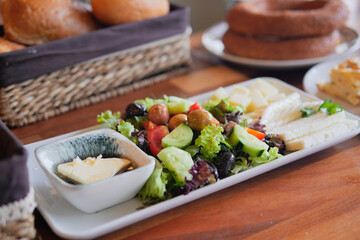 A Fresh Salad Platter featuring Dressing and an Assortment of Bread Rolls
