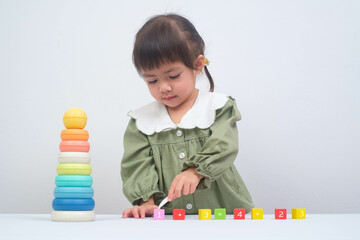 A young girl plays with colorful building blocks, enhancing her creativity and fine motor skills in...