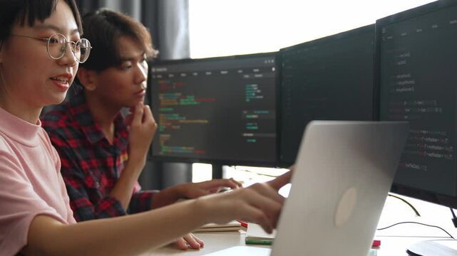 Slow motion back end software developer engineer for computer programming working together on debugging writing computing code, solving complex algorithms display on monitor in office. Burgeoning