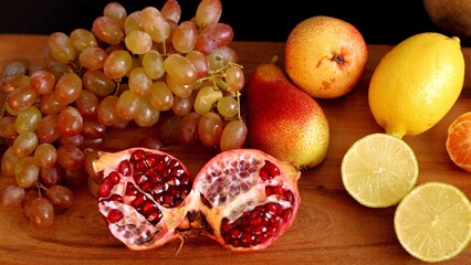 Fresh red grapes and yellow pear on wooden board create eco display, rich with natural colors. Organic produce promotes vibrant health, highlighting eco-friendly choices.