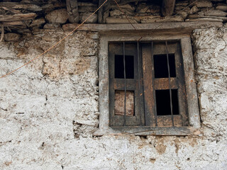 A window with four panes of glass is dirty and has a green frame spiti valley, India