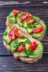 Avocado toast topped with tomato and green onion on a slice of carrot bread