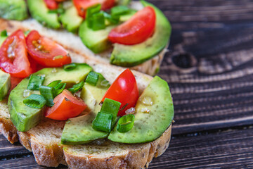 Avocado toast topped with tomato and green onion on a slice of carrot bread