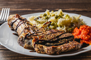 entrecote on the bone with rice and vegetables and adjika on a white plate