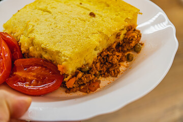 freshly prepared shepherd's pie with pickled tomatoes on a white plate