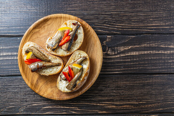 fish sandwich with butter and sprats, lemon on a wooden plate, top view