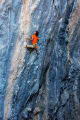 rock climber climbs on a rock. A strong man climbs a rock. Strong muscles. Endurance and strength training, man doing extreme sports.