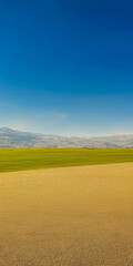 Fototapeta premium Scenic view of rolling hills and blue sky with a vibrant green field in daytime
