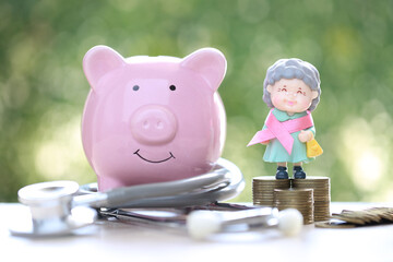 Symbol of breast cancer in women, Womaen and pink ribbon with piggy bank on green background, Healthcare and medicine concept