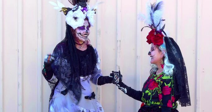 Young and old women with ceremonial traditional dress dance at Mexican Dia de los Muertos or Day of the Dead celebration in Los Angeles, California.