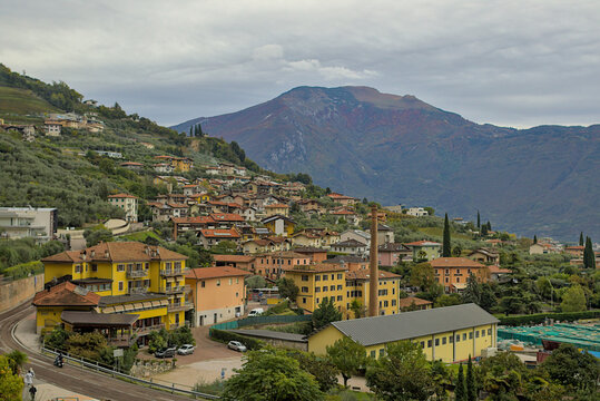 Varone Italy, a charming mountainside town. Colourful buildings with terracotta roofs line the slopes. The majestic mountains in the background add to the breathtaking beauty of this idyllic place.