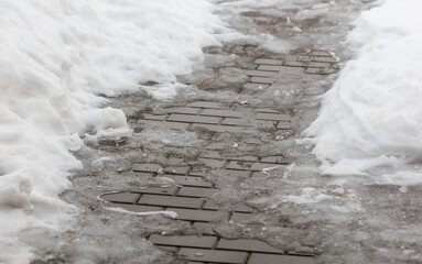 A brick walkway is covered in snow and ice