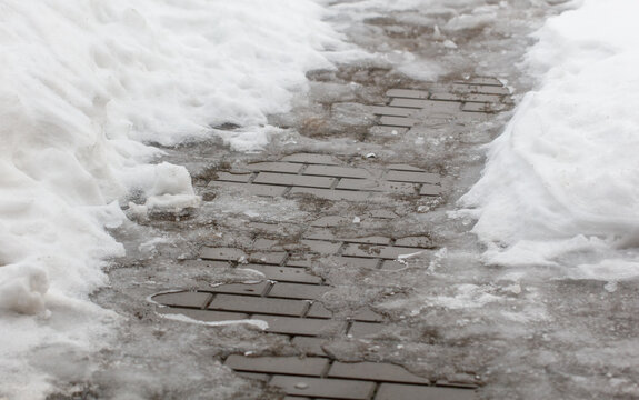 A brick walkway is covered in snow and ice