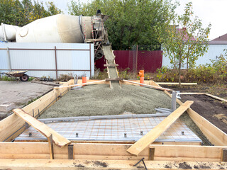 A cement mixer is pouring concrete into a hole in the ground