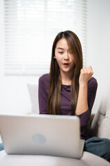 Excited woman looking at laptop screen, rejoicing good news, happy laughing girl reading email or message in social network, win online prize, great shopping offer, sitting on cozy sofa at home