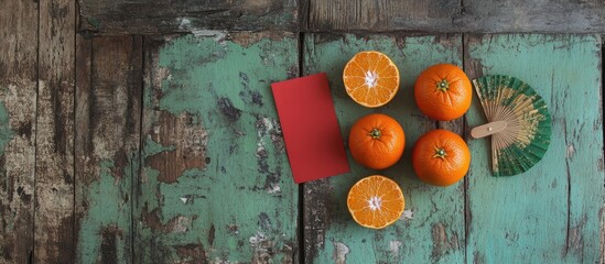 Chinese Lunar New Year backdrop with tangerines red envelope fan and traditional ornaments on rustic wooden surface