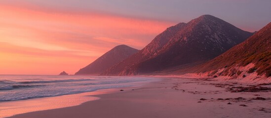 Serene early morning light illuminating a tranquil beach with mountains under a colorful dawn sky