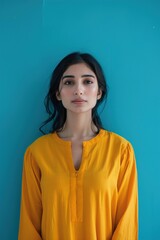 Fototapeta premium A female model in a bright, casual kurti with a minimalist design, against a solid turquoise background, capturing an easy-going and modern everyday style.