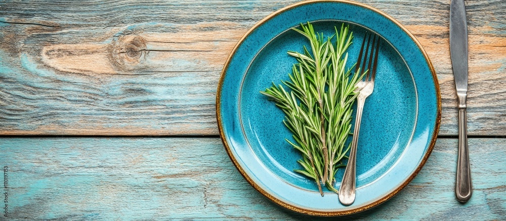 Poster rustic table setup with rosemary on blue plate and cutlery for a romantic dining experience top view