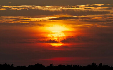 Obraz premium a sunset with clouds and trees