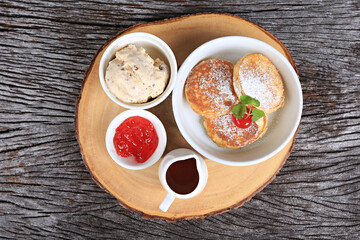 A set of snacks and sweets arranged on a wooden tray, including bread, jam and ice cream 