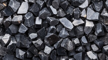 Black crushed stones used as ballast in railway tracks for stability and drainage in transportation infrastructure.