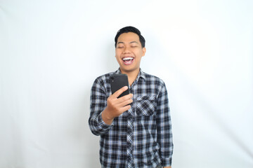 cheerful asian man laughing using smartphone wearing casual shirt isolated on white, joyful male texting on cell phone