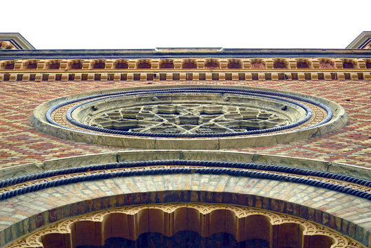 Photographed from the bottom up, a brick wall with a rose window and decorative cornices: the decoration above the portal of the Cetate Synagogue in Timisoara. Architectural landmarks in Romania.