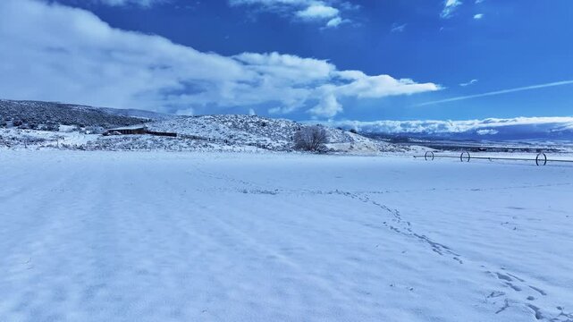 Aerial winter snow farm animal tracks valley. Storm and blizzard drops over a foot of fresh white snow. Rural farm community. Ranch farm, buildings, barns. Seasonal weather on livestock and wildlife.