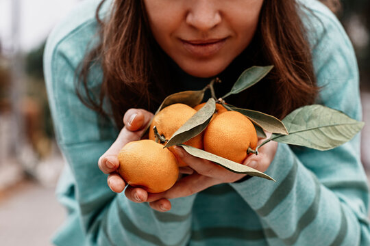 Woman holding fresh mandarins with leaves close-up