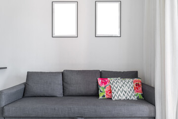 simple grey sofa in living room. upholstered furniture design. decorative pillows with colored pillowcases on sofa. There are lots of paintings on the wall. the interior of the apartment.