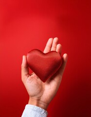 Obraz premium Hand holding a heart cover with red background and space for text