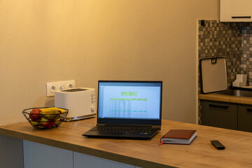 Laptop on the kitchen counter top with an excel sheet on computer screen showing bank loan amortization table. Concept